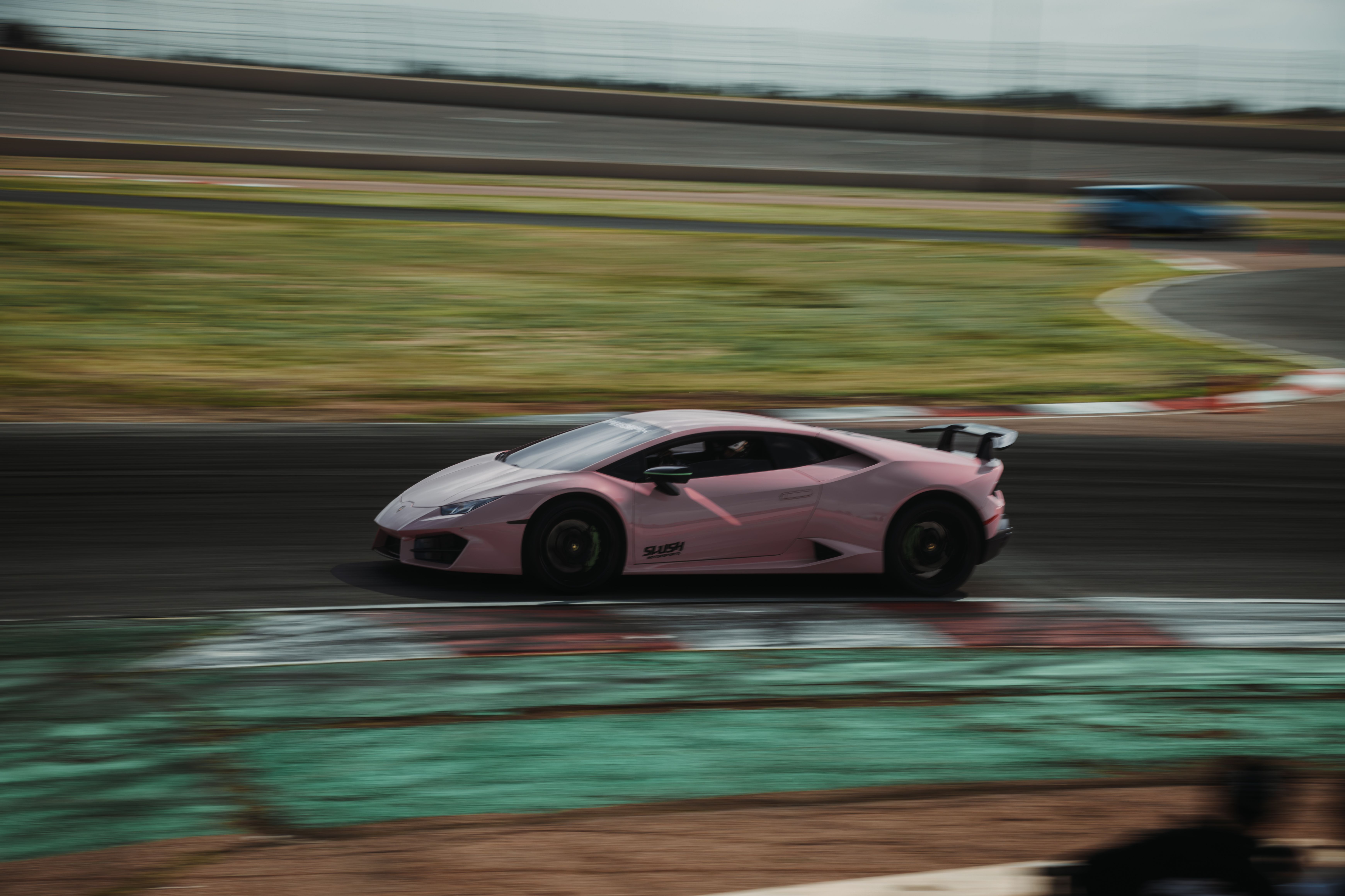 Pink Lamborghini Huracán on track, side profile in motion